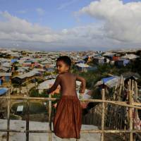 A Rohingya child stands on a bamboo fence overlooking an expanse of makeshift bamboo and tarp shelters at the Kutupalong refugee camp, where they have been living amid uncertainty over their future after they fled Myanmar to escape violence a year ago, in Bangladesh, Sunday. Myanmar court postpones verdict for Reuters journalists