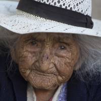 In this Aug. 23 photo, 117-year-old Julia Flores Colque eyes the camera while sitting outside her home in Sacaba, Bolivia. Her national identity card says Flores Colque was born on Oct. 26, 1900, in a mining camp in the Bolivian mountains. At 117 and just over 10 months, she would be the oldest woman in the Andean nation and perhaps the oldest living person in the world. Bolivian woman might be world's oldest person at nearly 118, and she's never heard of Guinness book