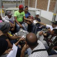 A Peruvian immigration officer checks the passports of Venezuelan migrants near Tumbes, Peru, Sunday as they sit in the back of the truck of a driver who picked them up after they crossed the border from Ecuador. Peru declares health emergency at border as exodus out of Venezuela nears 'crisis moment'
