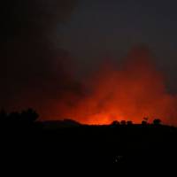 The red glow from a wildfire close to Monchique, in southern Portugal’s Algarve region, is seen on Saturday. With reading of 44 C, Portuguese capital's temperature record is broken