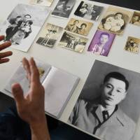 Hwang In-cheol displays old photos of his father in Seoul on Thursday. South Korean abductee families look on amid Korean War family reunions