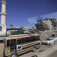 In a picture taken through a bus window, people drive in Damascus Monday. Syrian government officials vowed Monday to ensure the safe return of refugees and urged Western countries to encourage the process by lifting sanctions. Public Administration Minister Hussein Makhlouf said authorities are working to rebuild hospitals, schools and other infrastructure to help accommodate refugees. Syria vows to help refugees return, wants sanctions lifted but displaced seen as distrustful