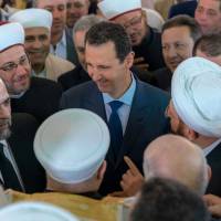 Syrian President Bashar Assad greets supporters during Eid al-Adha prayers at a mosque in Damascus on Tuesday. Standoff over Syria: U.S. and Russia trade chemical weapons warnings