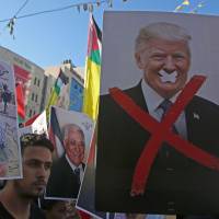 Palestinian protesters hold portraits of late Palestinian leader Yasser Arafat and U.S. President Donald Trump during a rally in support to the Fatah movement in the West Bank city of Nablus on July 17. Trump cuts more than $200 million in U.S. aid to Palestinians