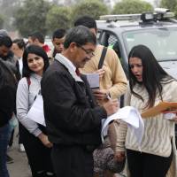 An officer checks the papers of Venezuelan migrants waiting to get a temporary residency permit at the Interpol headquarters in Lima on Thursday. Ecuador and Peru tighten entry requirements for Venezuelans as influx swells