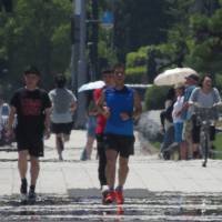 A haze caused by extreme heat can be seen as pedestrians walk along a street during high temperatures in Tokyo on Aug. 2. Olympic heat wave fears: What steps can Tokyo take?