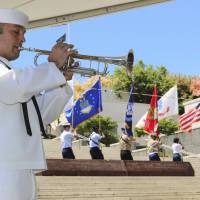 A sailor plays taps during a ceremony at the National Memorial Cemetery of the Pacific in Honolulu on Wednesday. U.S. POWs, killed in 1945 attack on Japanese ship and buried as unknowns, get memorial marker in Hawaii