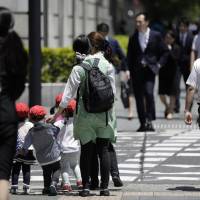Day care workers get ready to guide a group of children across a Tokyo street in June 2017. Japan could take a page from France’s book when it comes to raising the fertility rate. Address Japan's demographic, fiscal woes