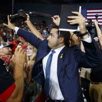 A staff member for U.S. President Donald Trump blocks a camera as a photojournalist attempts to take a photo of a protester during a rally in Evansville, Indiana, on Thursday. Can U.S. media stand up for press freedom?