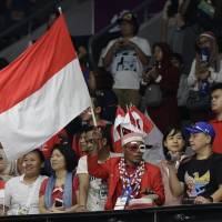 A fan waves an Indonesian flag during the men’s team badminton final between Indonesia and China at the Asian Games in Jakarta on Aug. 22. Passionate Indonesian fans embrace home Asian Games