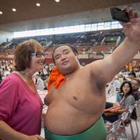 Takakeisho takes a picture with a fan at a regional tour event in Sendai in this August 2016 file photo. Grueling summer tours offer mixed blessing for sumo