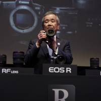 Masaya Maeda, president and chief operating officer of Canon Inc., holds a Canon EOS R, the company’s new mirrorless digital camera, at an unveiling event in Tokyo Wednesday. Canon joins Sony and Nikon in battle for pro-grade mirrorless camera market