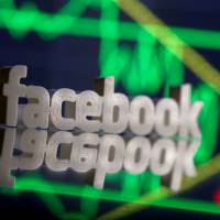 A 3D-printed Facebook logo is seen in front of displayed stock graph in this illustration photo in March. Google, Facebook and Twitter agree to code of conduct to fight fake news in EU