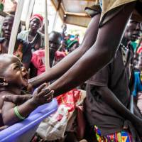 A mother weighs her malnourished child in a nutrition center run by the International Rescue Committee (IRC) in Panthau, Northern Bahr al Ghazal, South Sudan, in 2017. Microsoft, Amazon, Google join fight to prevent famine, tap AI tech