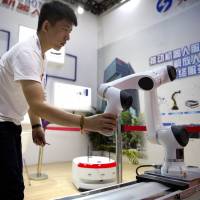 A visitor looks at a robotic manufacturing arm from Chinese robot maker Han’s Robots at the World Robot Conference in Beijing in August. As Trump threatens tariffs, China's industrial ambitions loom large