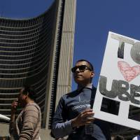 An Uber supporter holds a placard during a rally in front of Toronto’s City Hall in 2015. Uber revs up Canadian operations with new AI funding for Toronto self-driving car lab