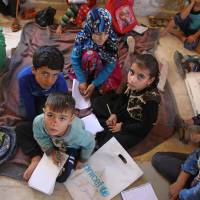 Displaced Syrian children attend class at a makeshift school in the village of Muhandiseen, in the south western countryside of Aleppo province, on Monday. In abandoned villa, war-displaced Syrian kids study on the ground