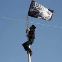 A member of al-Qaida’s Nusra Front climbs a pole where a Nusra flag was raised at a central square in the northwestern city of Ariha, Syria, after a coalition of insurgent groups seized the area in Idlib province in 2015. American al-Qaida recruit tells of training and 'terrible boredom' waiting for mission
