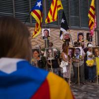 Protesters hold placards with portraits of Catalan separatist leaders imprisoned, during a demonstration to mark 11 months of imprisonment for some of their leaders, in Barcelona, Spain, Sunday. Eight former members of the ousted Catalan regional government and two leaders of secessionist grassroots groups are still on jail while they are investigated for possible sedition and rebellion charges. Barcelona police keep apart Catalan separatists from pro-Spain unity crowd