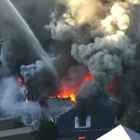 Flames consume the roof of a home in Lawrence, Massachusetts, a suburb of Boston, on Thursday. A series of gas explosions killed a teenager, injured at least 10 other people and ignited fires in at least 39 homes in three communities north of Boston, forcing entire neighborhoods to evacuate as crews scrambled to fight the flames and shut off the gas. Officials work to pinpoint cause of 'Armageddon'-like gas explosions near Boston