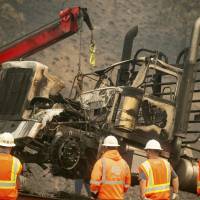A crane lifts a truck scorched by the Delta Fire on Interstate 5 in the Shasta-Trinity National Forest, California, on Thursday. The highway remains closed to traffic in both directions as crews battle the blaze. Truckers abandon big rigs as wildfire scorches California freeway I-5