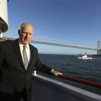 California Gov. Jerry Brown walks to the bow of a high-tech battery-operated San Francisco Bay sightseeing boat, Enhydra, for a cruise of San Francisco Bay on Thursday, when he signed 16 new laws aimed at easing global warming. 'Gov. Moonbeam' says California to launch climate satellite
