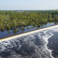 In this drone photo released by Duke Energy, flooding from the swollen Cape Fear River overtops an earthen dike at Sutton Lake, a 1,100-acre (445-hectare) lake at the L.V. Sutton Power Station near Wilmington, North Carolina, Thursday. Duke Energy activated a high-level emergency alert at the retired coal-fired power plant due to the flooding, raising concerns of a potential breach. Floodwaters inundate lake at retired North Carolina power plant, threatening dam