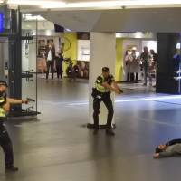 Dutch police officers point their guns at a wounded 19-year-old man who was shot by police after stabbing two people in the central railway station in Amsterdam Friday. Police investigators in Amsterdam included an extremist attack as a possible motive for the stabbings of two people at the busy railway station Friday as authorities in the Dutch capital reported that the suspect shot by police is an Afghan citizen. Dutch police grill suspect in stabbings of two Americans in alleged terrorist attack at station
