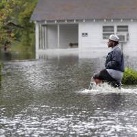 Rockeem Williams walks down a street through floodwaters from Hurricane Florence, in Marion, South Carolina, Sunday. 'Angry waters' as killer storm Florence floods Carolinas, cuts Wilmington off