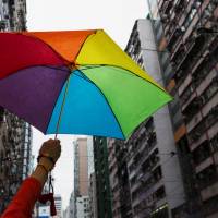 A participant holds a rainbow umbrella as he attends a lesbian, gay, bisexual and transgender Pride Parade in Hong Kong on Nov. 8, 2014. Hong Kong to allow dependent visa for same-sex couples after landmark ruling