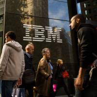 Pedestrians walk past the IBM logo displayed at the company’s offices in New York, U.S., in 2013. IBM sued for age discrimination after firing over 20,000 staff over 40 in six years