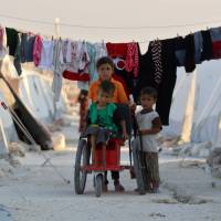 Displaced Syrian children push a disabled boy on a makeshift wheelchair at a camp in Idlib province on Wednesday. UNICEF warns 1 million Syrian children are at risk if Idlib assault happens