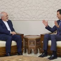 Syrian President Bashar Assad gestures in a meeting with Iran’s Foreign Minister Mohammad Javad Zarif in Damascs Monday. Militants must be 'cleaned out' of Syria's Idlib, Iran says