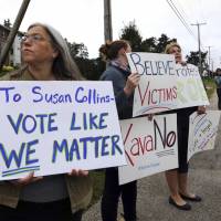 Demonstrators hold signs outside Saint Anselm College in Manchester, New Hampshire, on Friday, where U.S. Sen. Susan Collins, considered one of the few possible Republican “no” votes on Supreme Court nominee Brett Kavanaugh, was scheduled to speak. GOP, Supreme Court nominee accuser Christine Ford in standoff over her testimony before Senate