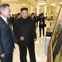 South Korean President Moon Jae-in and North Korean leader Kim Jong Un look at a painting of themselves shaking hands as they arrive to attend a welcome banquet in Pyongyang on Tuesday. Inter-Korean summit may be the grand theater Kim needs to show his people
