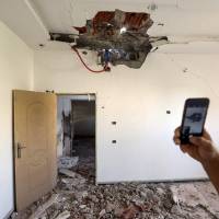A hole is seen Tuesday in the ceiling of a house that was hit by a rocket in the southern suburb of Ayn Zarah on the outskirts of the Libyan capital Tripoli. — The U.N. mission in Libya said on Tuesday it had brokered a cease-fire to end a week of clashes in the capital that have killed dozens and forced thousands to flee their homes, whom the Libyan health ministry had said were mostly civilians. Cease-fire holds in Libya after Tripoli clashes kill scores: U.N.