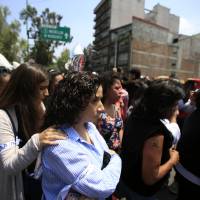 Victims’ family members comfort each other as they return to a memorial ceremony in front of the site at Alvaro Obregon 286, where 49 died when their office building collapsed in last year’s 7.1 magnitude earthquake, after participating in a city-wide earthquake drill in Mexico City Wednesday. Across the city, memorials were held at sites where hundreds perished in the Sept. 19, 2017, quake. Mexico marks anniversaries of two deadly earthquakes, then holds drill
