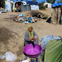 A migrant empties a bottle of water in a bucket at a makeshift camp next to the Moria camp for refugees and migrants on the island of Lesbos, Greece, Tuesday. Out of the frying pan: Europe's solutions to migration seen creating greater humanitarian crises