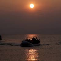 Refugees and migrants approach the Greek island of Lesbos on a dinghy at sunrise on March 20, 2016. Migrant crisis haunts EU three years after Merkel's fateful call