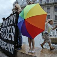 Gay rights activists protest proposed changes to the constitution that would prevent future recognition of same-sex marriages, in Bucharest Tuesday. Romanian senators on Tuesday approved a measure that would pave the way for the constitution, which currently states that marriage is a union between “spouses,” to be changed to explicitly state that marriage is a union of a man and a woman. Banner Reads “Until we are all free — We are all prisoners.” Romania legislature votes in favor of man-woman marriage only, paves way for referendum