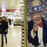 People walk past a caricature of U.S. President Donald Trump on sale in a shopping mall in Moscow in 2017. China and Russia warn U.S. of consequences over sanctions