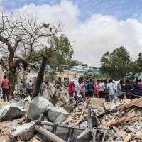 Somalis gather at the car bombing site outside of a local government office in Mogadishu on Monday. According to Somali police and rescue workers, six people were killed and 16 were injured by the explosion. Al-Shabab takes credit as car bomb kills six outside Somali government office