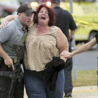 A women is escorted from the scene of a shooting at a software company in Middleton, Wisconsin, Wednesday. Four people were shot and wounded during the shooting in the suburb of Madison, according to a city administrator. Three wounded in shooting at Wisconsin software business; gunman killed