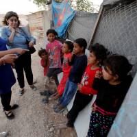 Members of a delegation of the European Parliament speak with Palestinian children during a visit to the Palestinian Bedouin village of Khan al-Ahmar, in the occupied West Bank, Wednesday. Eight EU countries urge Israel to reconsider razing Palestinian village