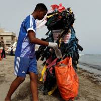 Modou Fall, head of the Clean Senegal Association, wears a costume made from plastic cups and bags as he helps clean a beach during World Cleanup Day in Dakar on Sept. 15. With population boom, urbanization, World Bank warns waste could grow 70% by 2050