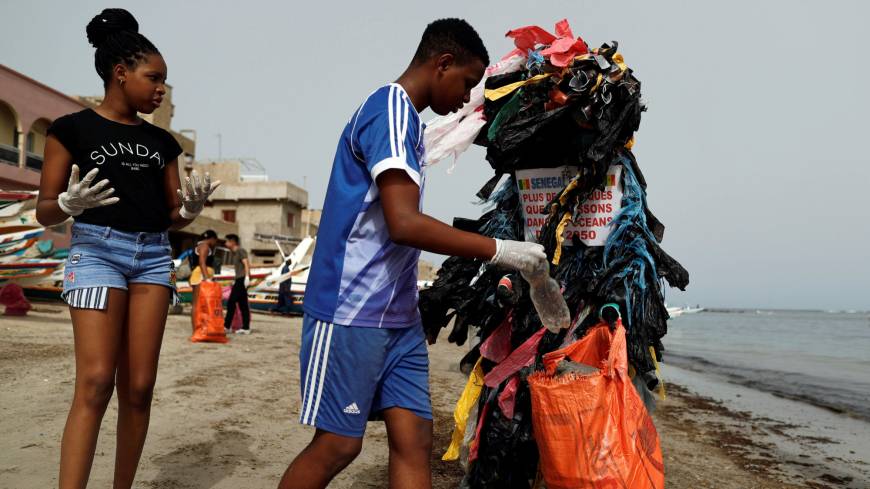 Modou Fall, head of the Clean Senegal Association, wears a costume made from plastic cups and bags as he helps clean a beach during World Cleanup Day in Dakar on Sept. 15. With population boom, urbanization, World Bank warns waste could grow 70% by 2050