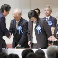 Prime Minister Shinzo Abe shakes hands with relatives of those abducted by North Korean agents decades ago, during an event in Tokyo on Sunday. Families of Japanese abductees renew call for increased efforts to secure their return