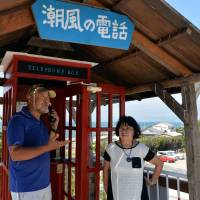 Tomohiko Kutsuna and his wife, Kazuko, stand in front of a telephone booth they set up on a hill in Tahara, Aichi Prefecture, as a place to speak to a prior student who took her own life in 2009. Aichi couple sets up phone booth for people seeking to connect with loved ones they have lost