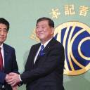 Prime Minister Shinzo Abe, current president of the ruling Liberal Democratic Party, and former defense chief Shigeru Ishiba shake hands in Tokyo on Friday prior to a debate ahead of the Sept. 20 LDP presidential election.