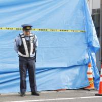 A woman puts her hands on her face outside a police box in Miyagino Ward, Sendai, on Thursday morning, a day after a police officer was fatally stabbed there. Sendai policeman's killer may have tried to steal officer's gun